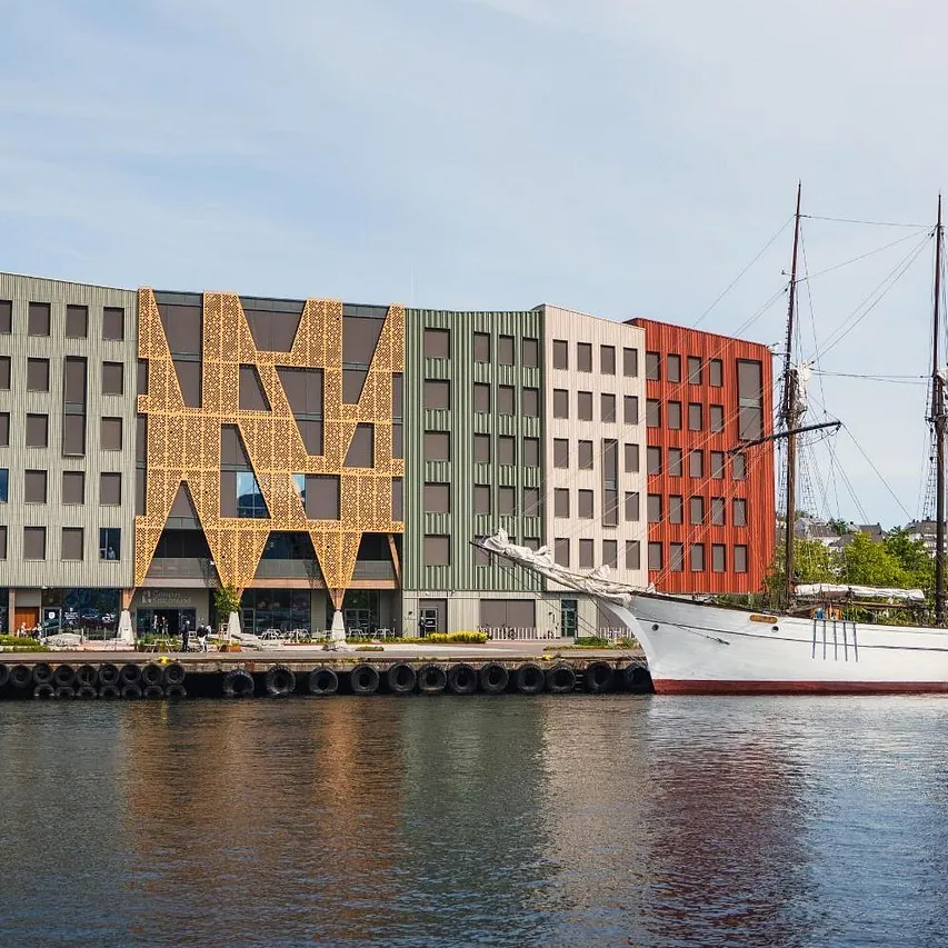 Campus Kristiansund fasade ved vannet, med stort hvitt treskip utenfor